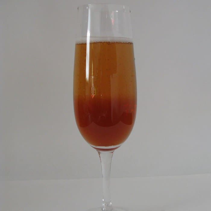 Kir Royale cocktail in champagne flute with lime wheel